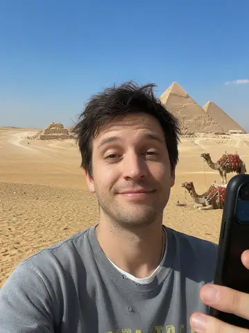 Exempel på Pyramiderna: Personen står i den egyptiska öknen med de stora pyramiderna och ett par kameler bakom sig en solig dag.